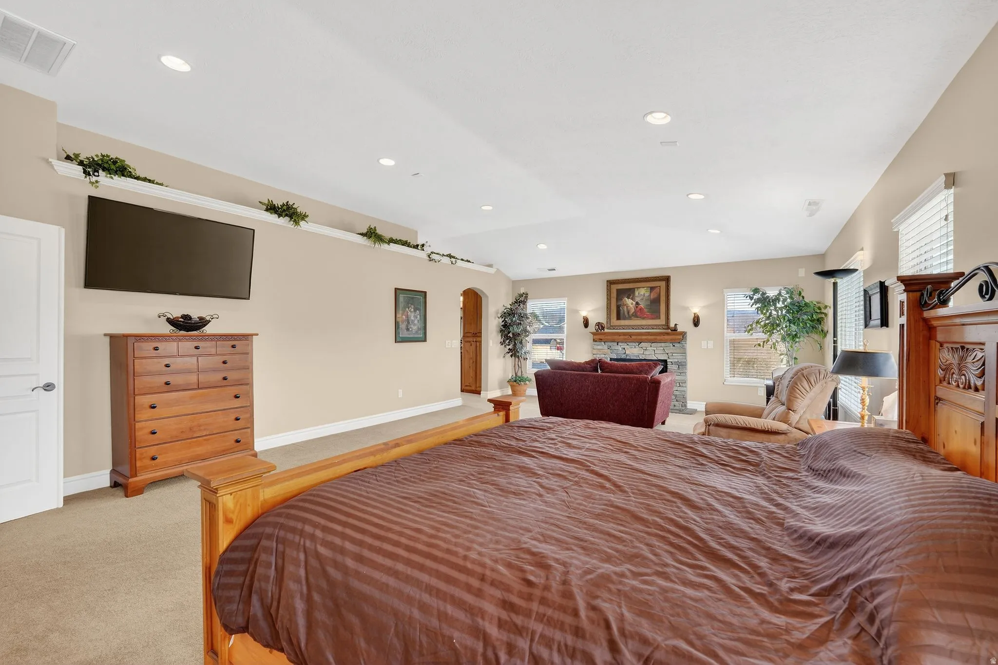 Bedroom with light colored carpet, a fireplace, and recessed lighting