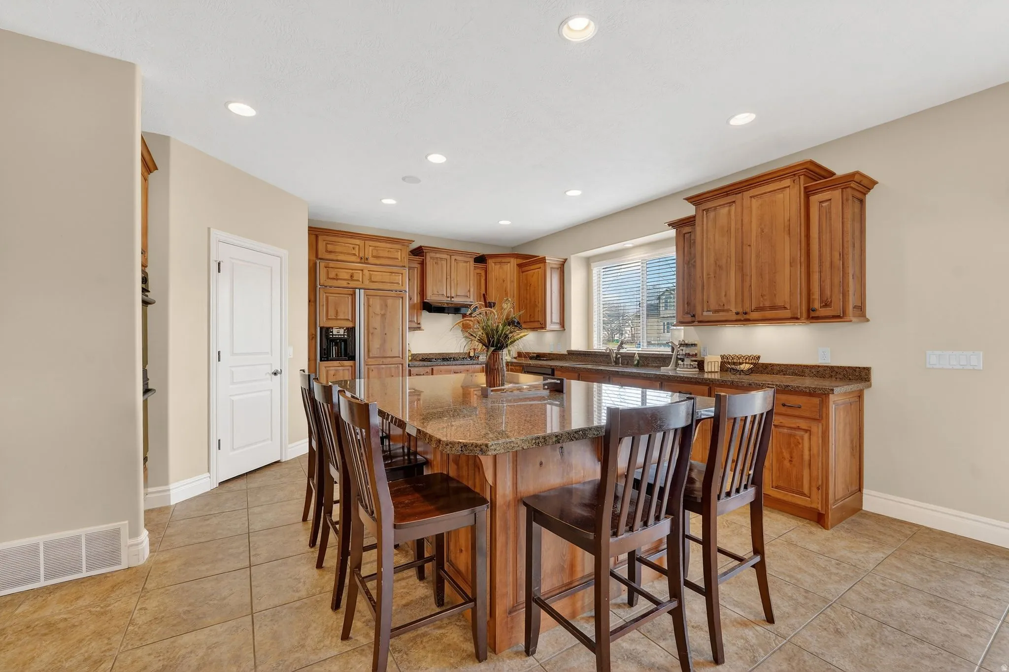Kitchen with wood finish cabinetry, a kitchen bar, dark stone counters, a kitchen island, and light tile patterned flooring