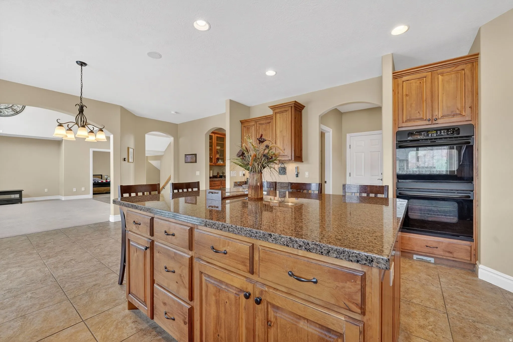 Kitchen with wood finish cabinets, a center island, dark stone countertops, and hanging light fixtures
