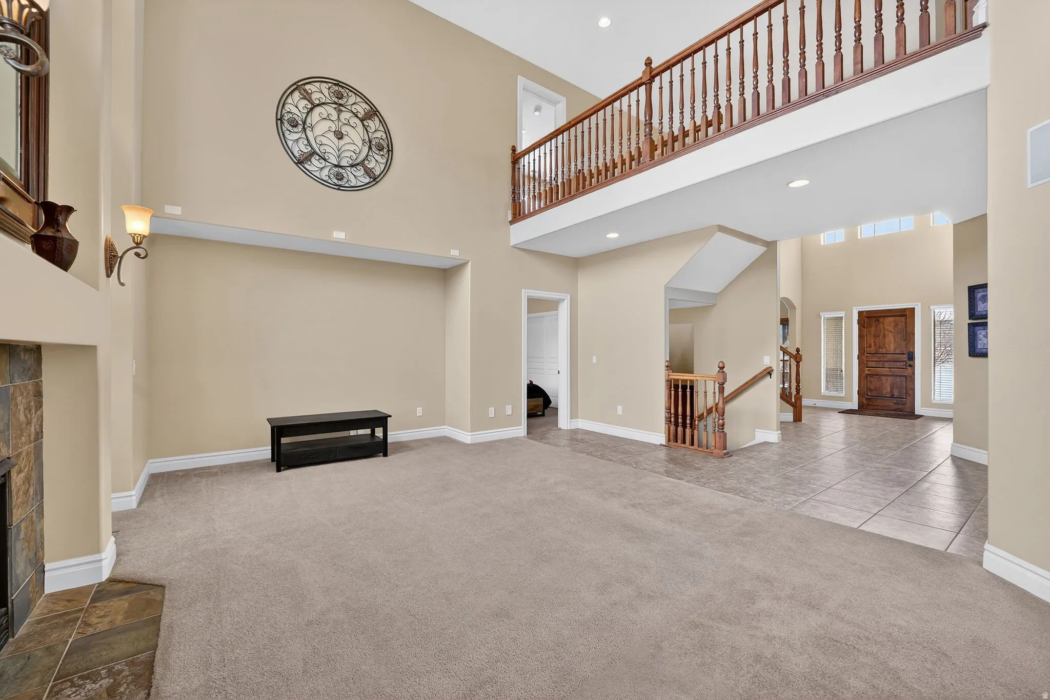 Unfurnished living room featuring a tiled fireplace, carpet, a high ceiling, and recessed lighting