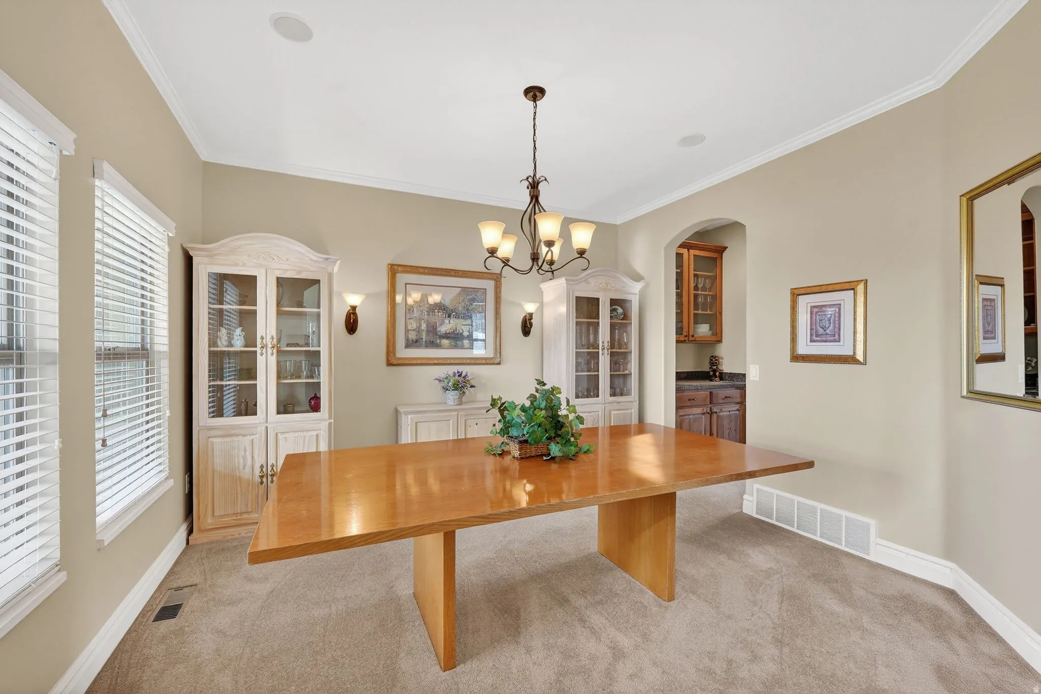 Dining area with light carpet, hanging lights, and ornamental molding