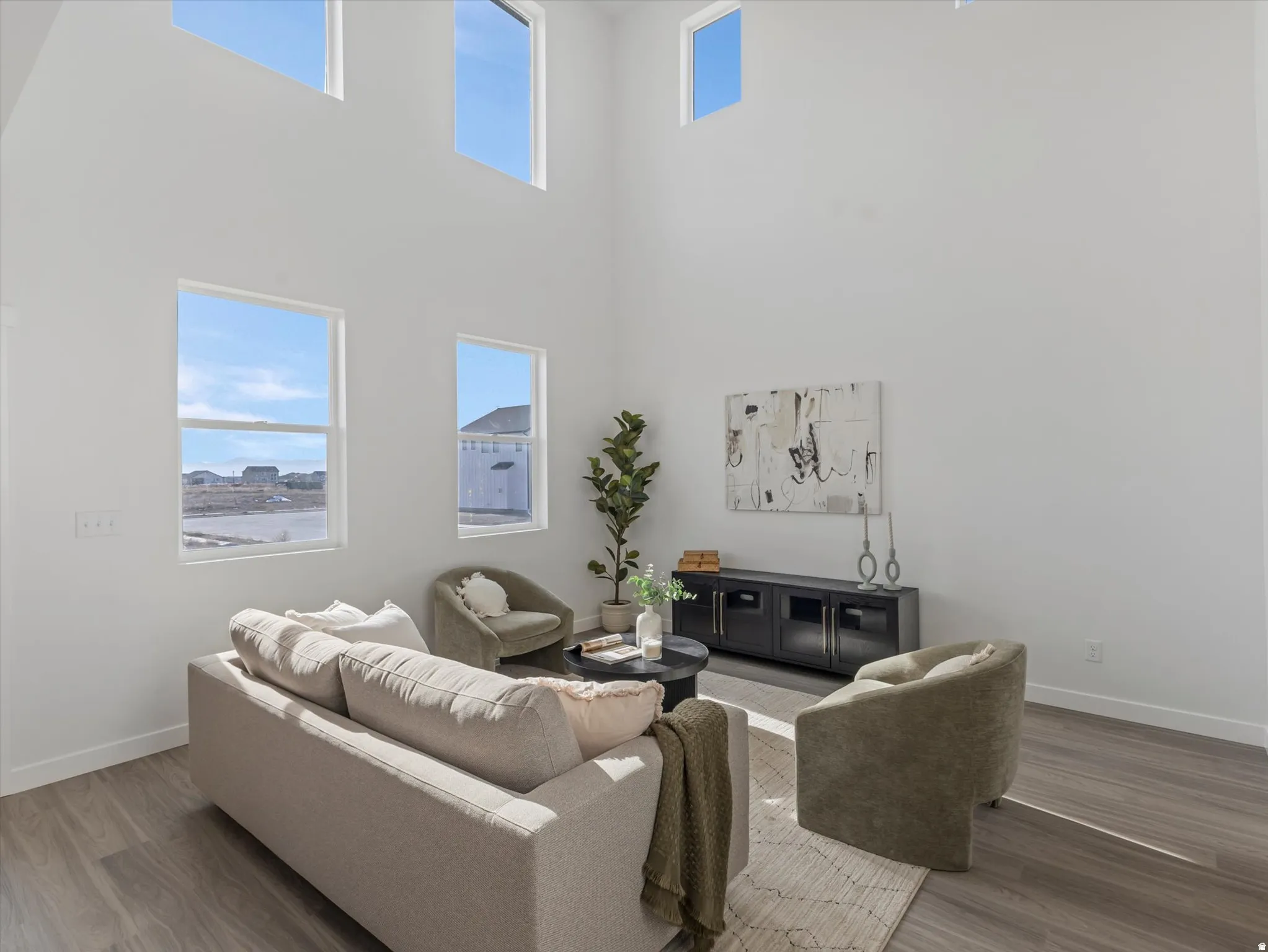 Living area with healthy amount of natural light, a high ceiling, and wood finished floors