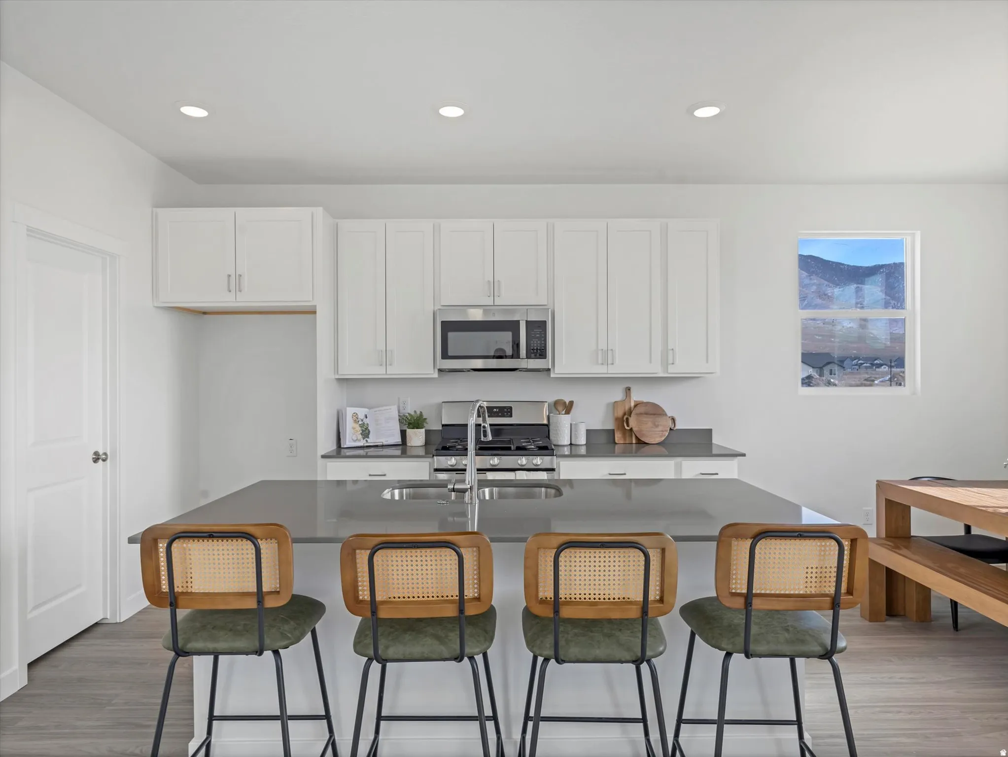 Kitchen featuring white cabinets, dark wood-style flooring, a center island with sink, and recessed lighting