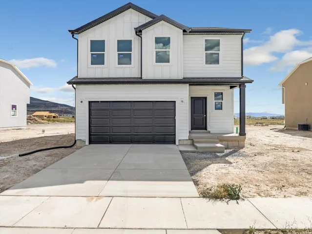 View of front of home featuring an attached garage, concrete driveway, a mountain view, and board and batten siding