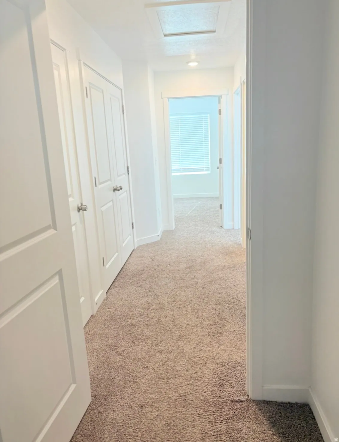 Hallway with light carpet and baseboards