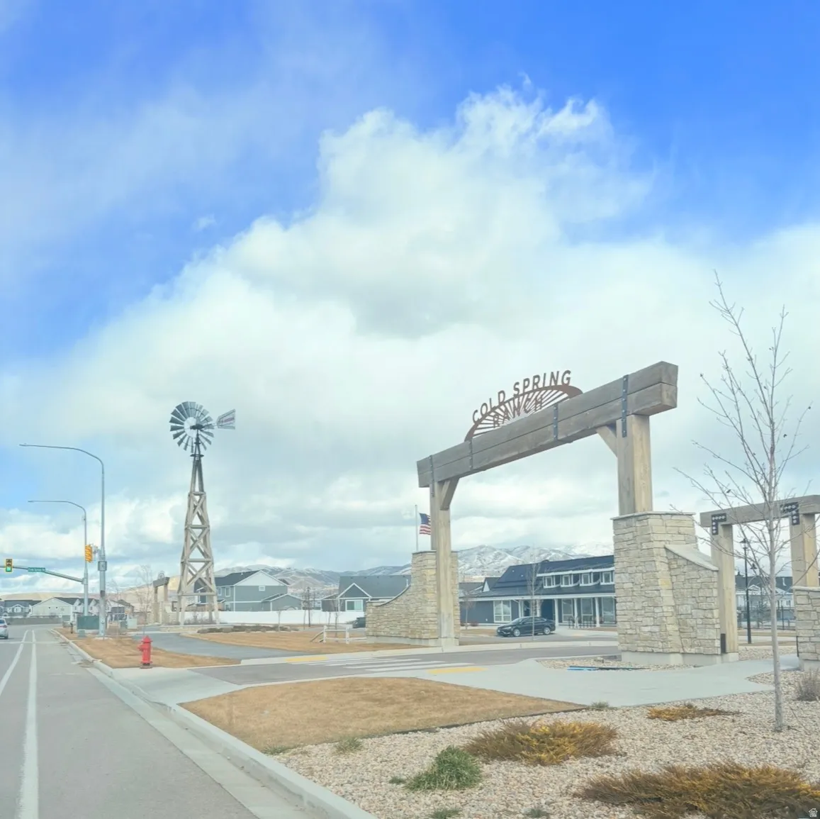 View of asphalt road with curbs, street lights, and sidewalks