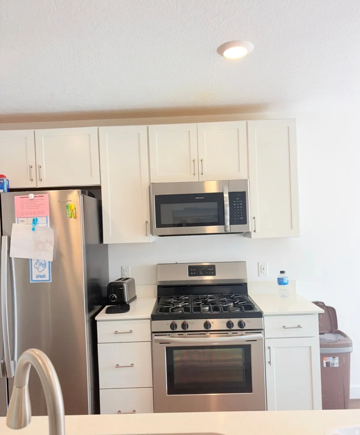 Kitchen featuring stainless steel appliances, white cabinetry, and a textured ceiling