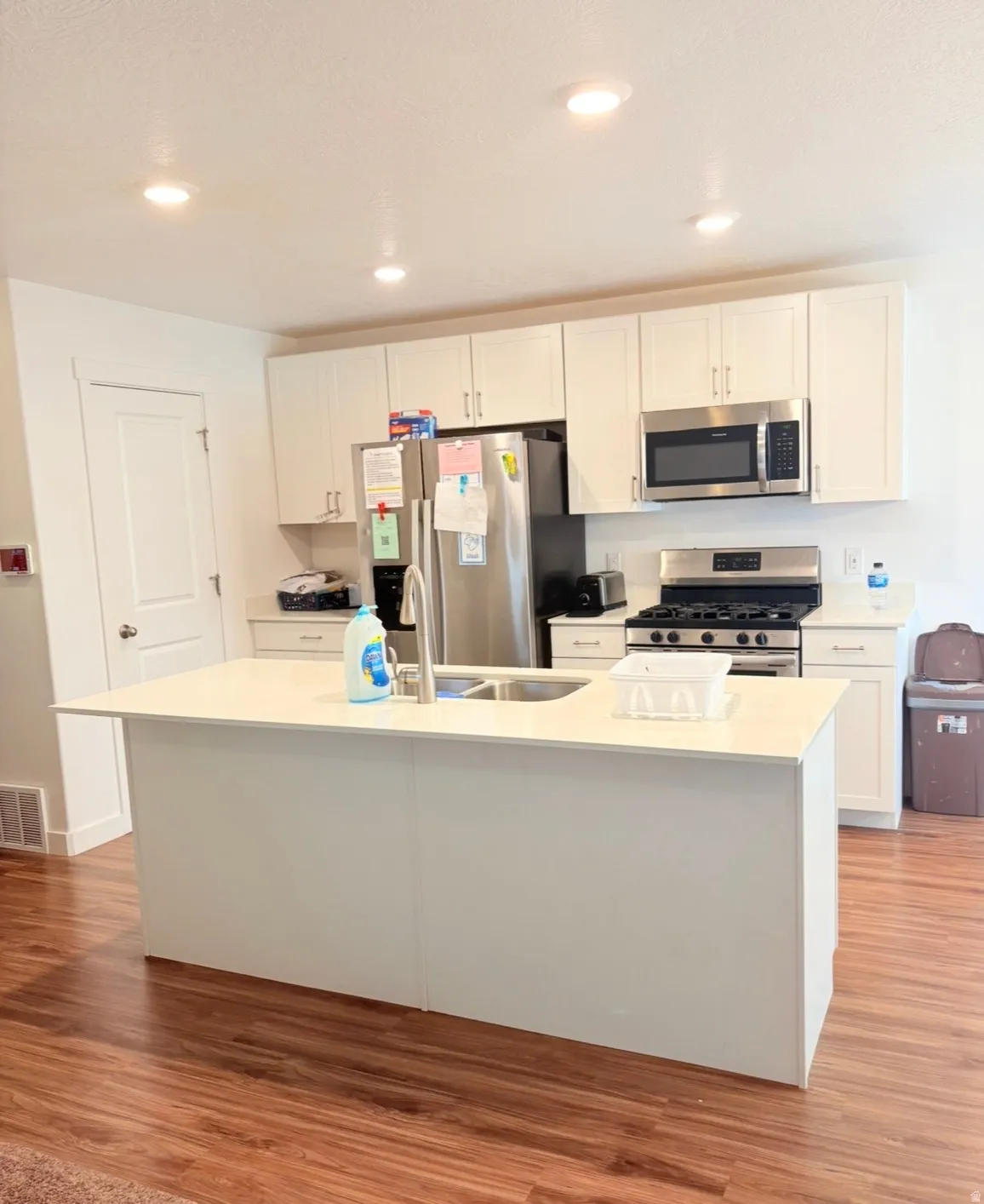 Kitchen featuring white cabinets, stainless steel appliances, an island with sink, and recessed lighting