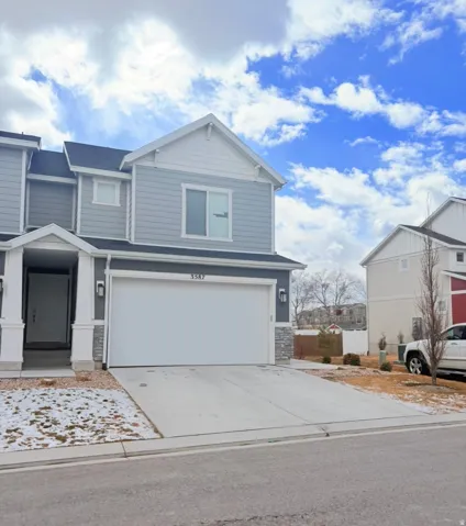 View of front of home with driveway, stone siding, and an attached garage