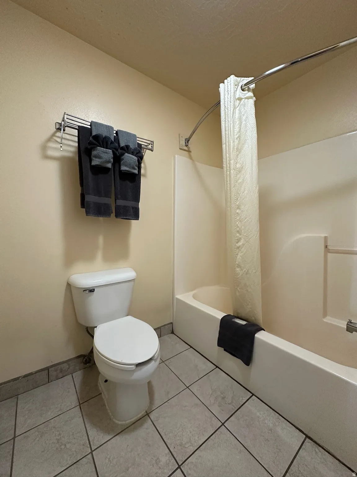 Full bathroom featuring shower / bath combo with shower curtain and light tile patterned flooring