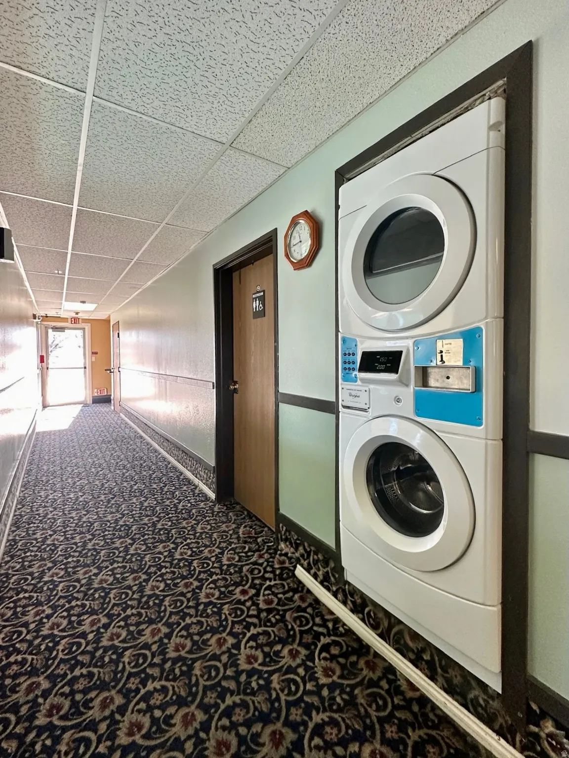 Laundry area featuring a drop ceiling and stacked washer / dryer