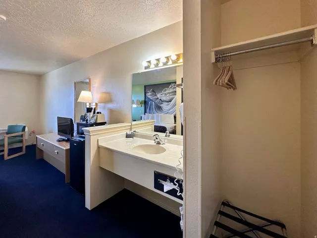 Bathroom featuring vanity, a textured ceiling, dark carpet, and a textured wall