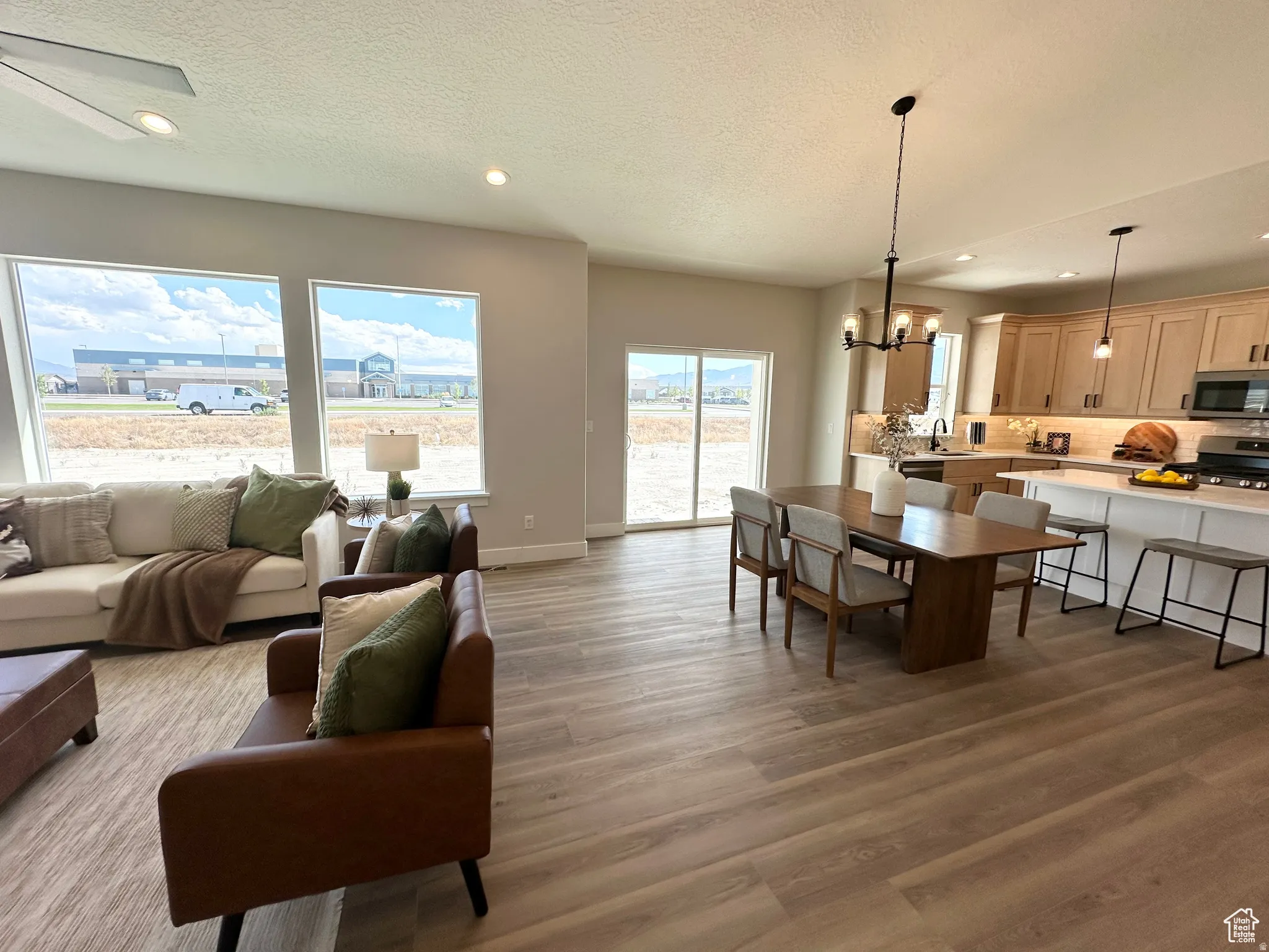 Living area featuring suspended lighting, a textured ceiling, and light wood-style floors