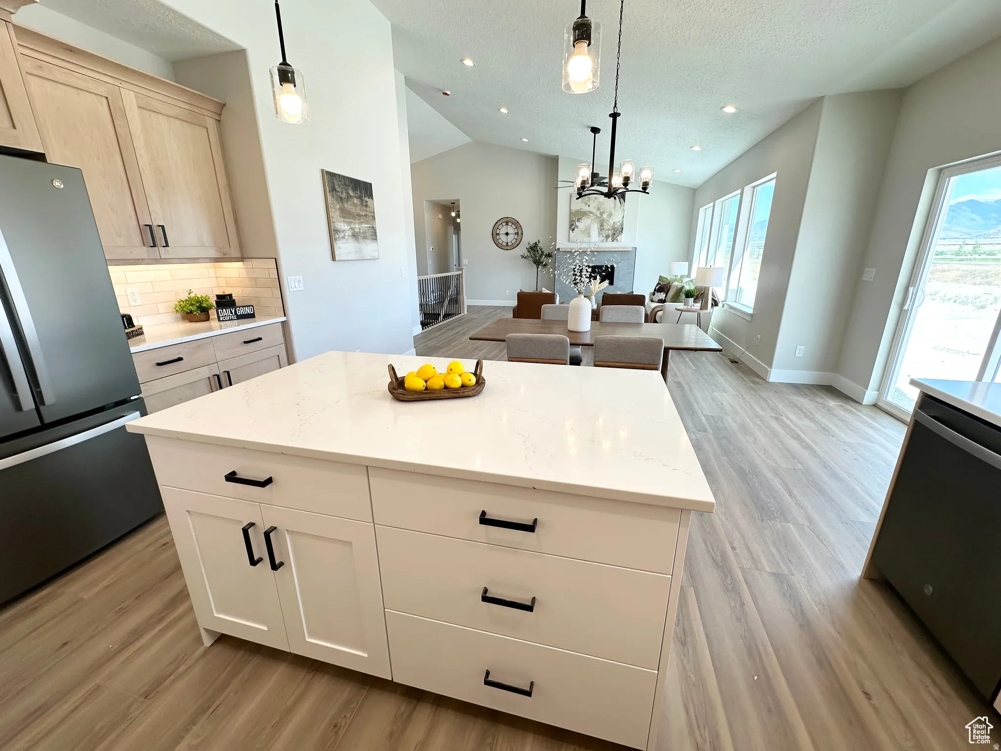 Kitchen featuring stainless steel appliances, open floor plan, light wood-style flooring, a fireplace, and tasteful backsplash