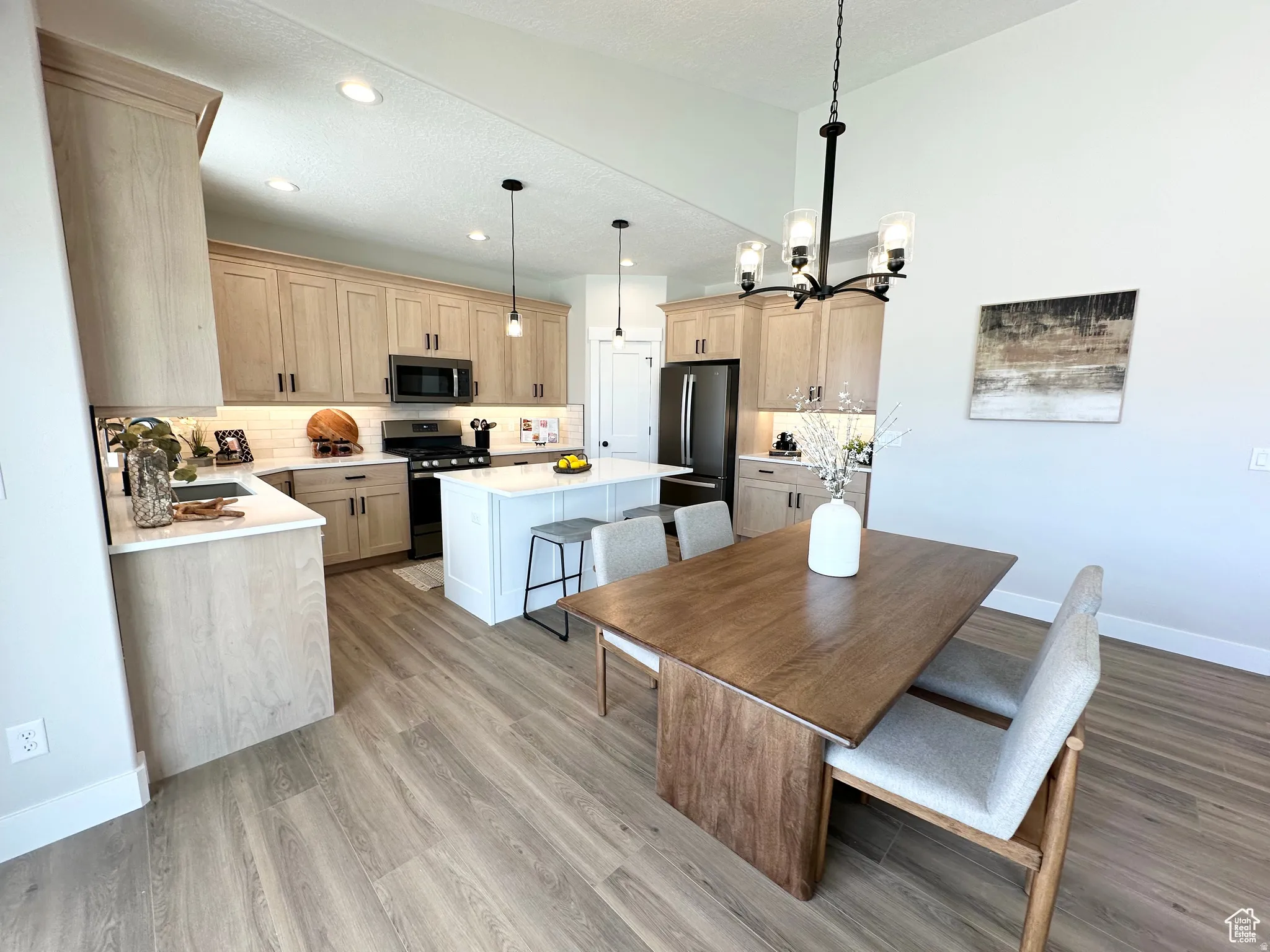 Dining space featuring light wood-style floors, hanging lights, and a textured ceiling