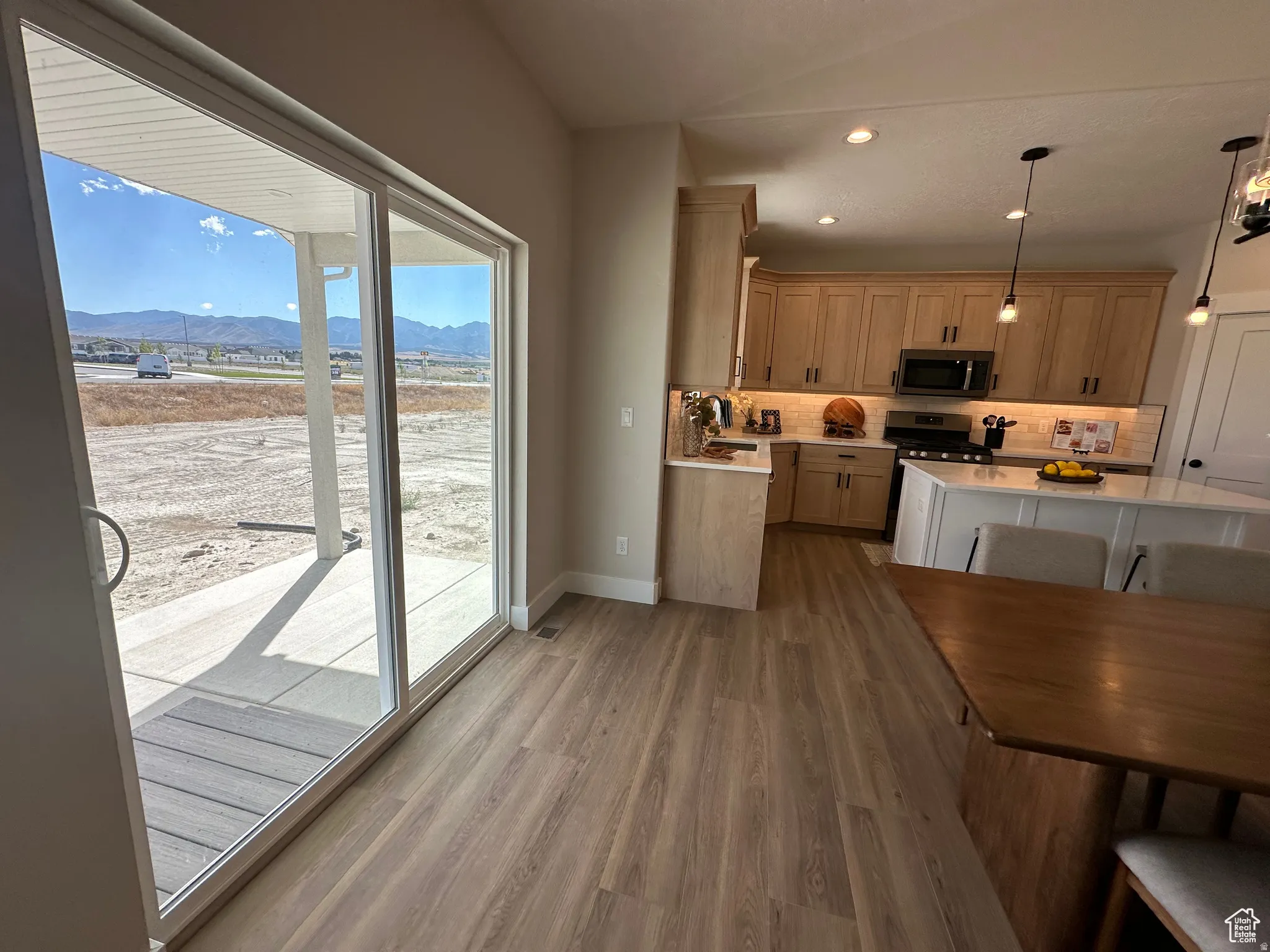 Kitchen featuring a mountain view, dark wood-style floors, light stone countertops, stainless steel microwave, and hanging light fixtures