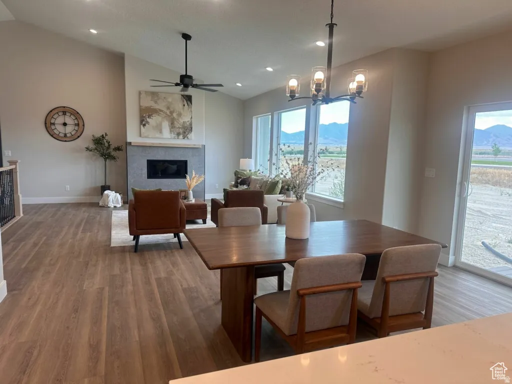 Dining area featuring wood finished floors, a glass covered fireplace, ceiling fan, a mountain view, and lofted ceiling