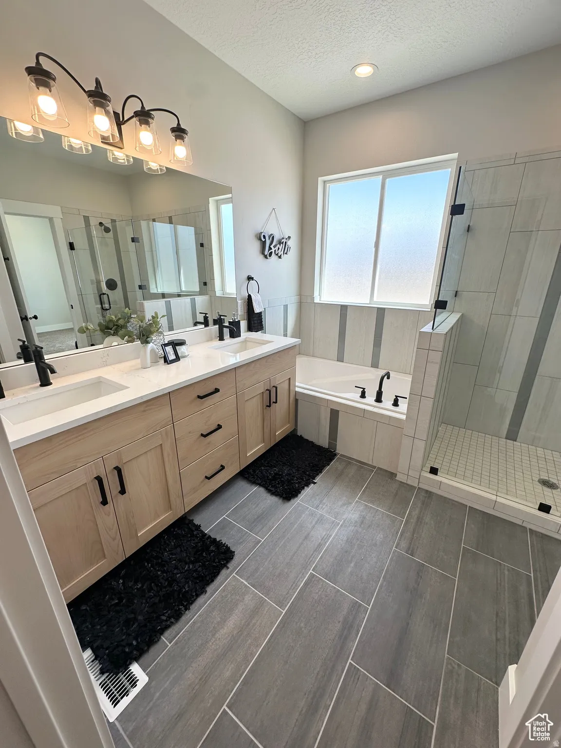 Full bath with a shower stall, a bath, double vanity, and a textured ceiling