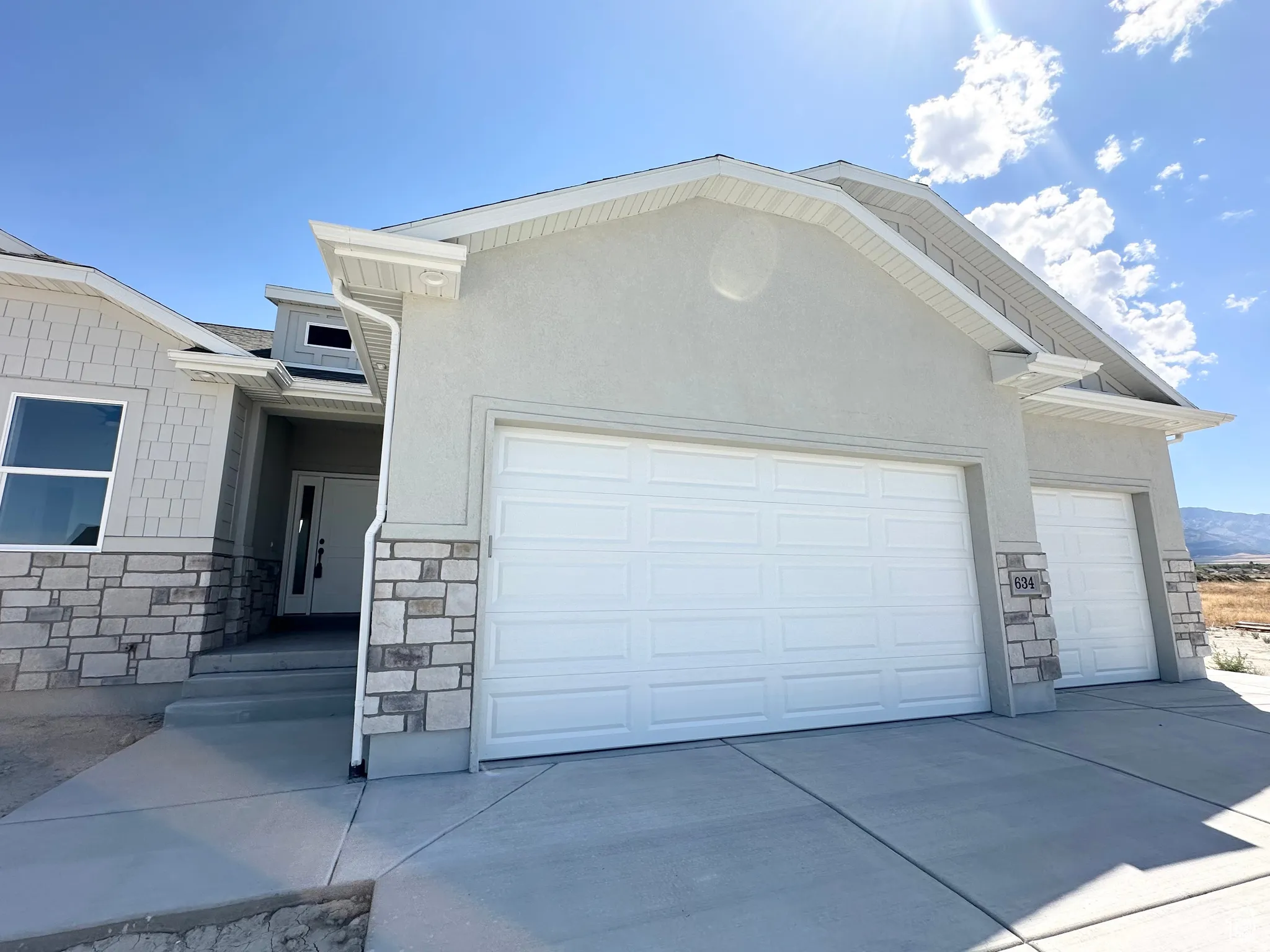 View of front facade with a garage, stone siding, and concrete driveway