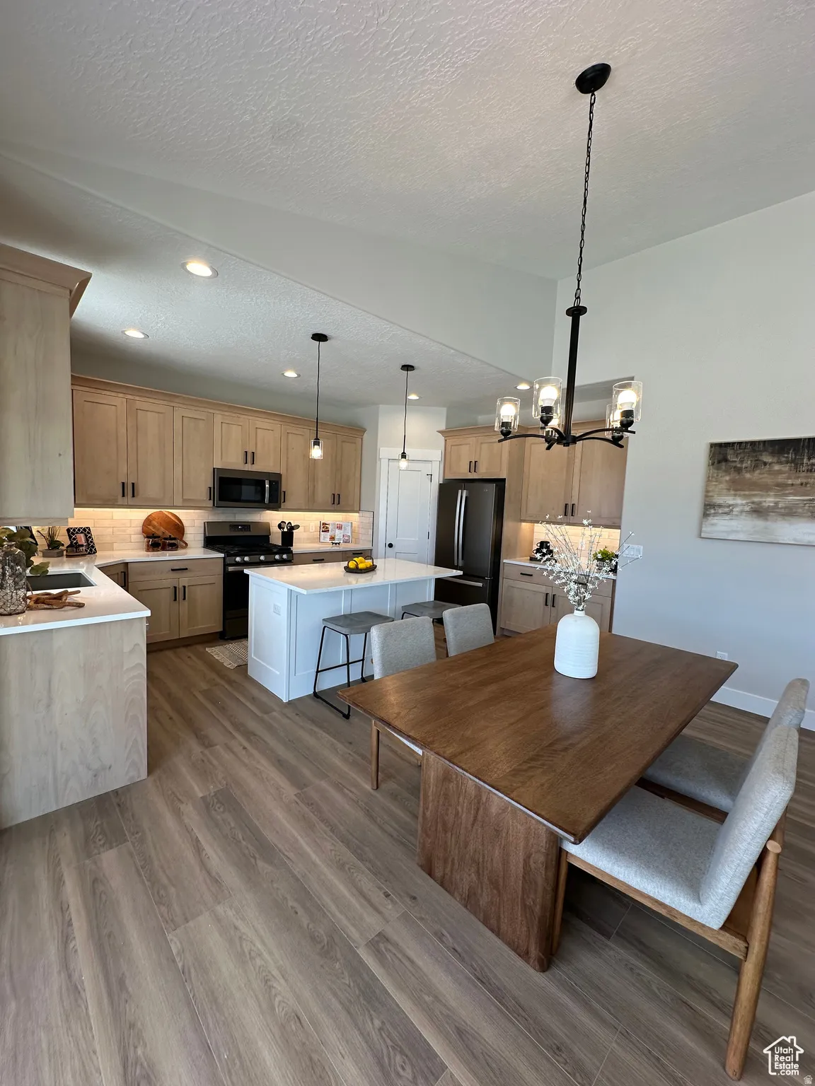 Dining area featuring a textured ceiling, suspended lighting, and dark wood-type flooring