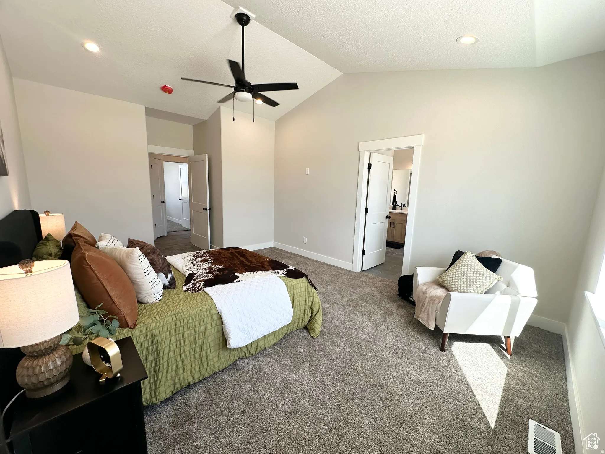 Carpeted bedroom with a ceiling fan, ensuite bathroom, a textured ceiling, and recessed lighting