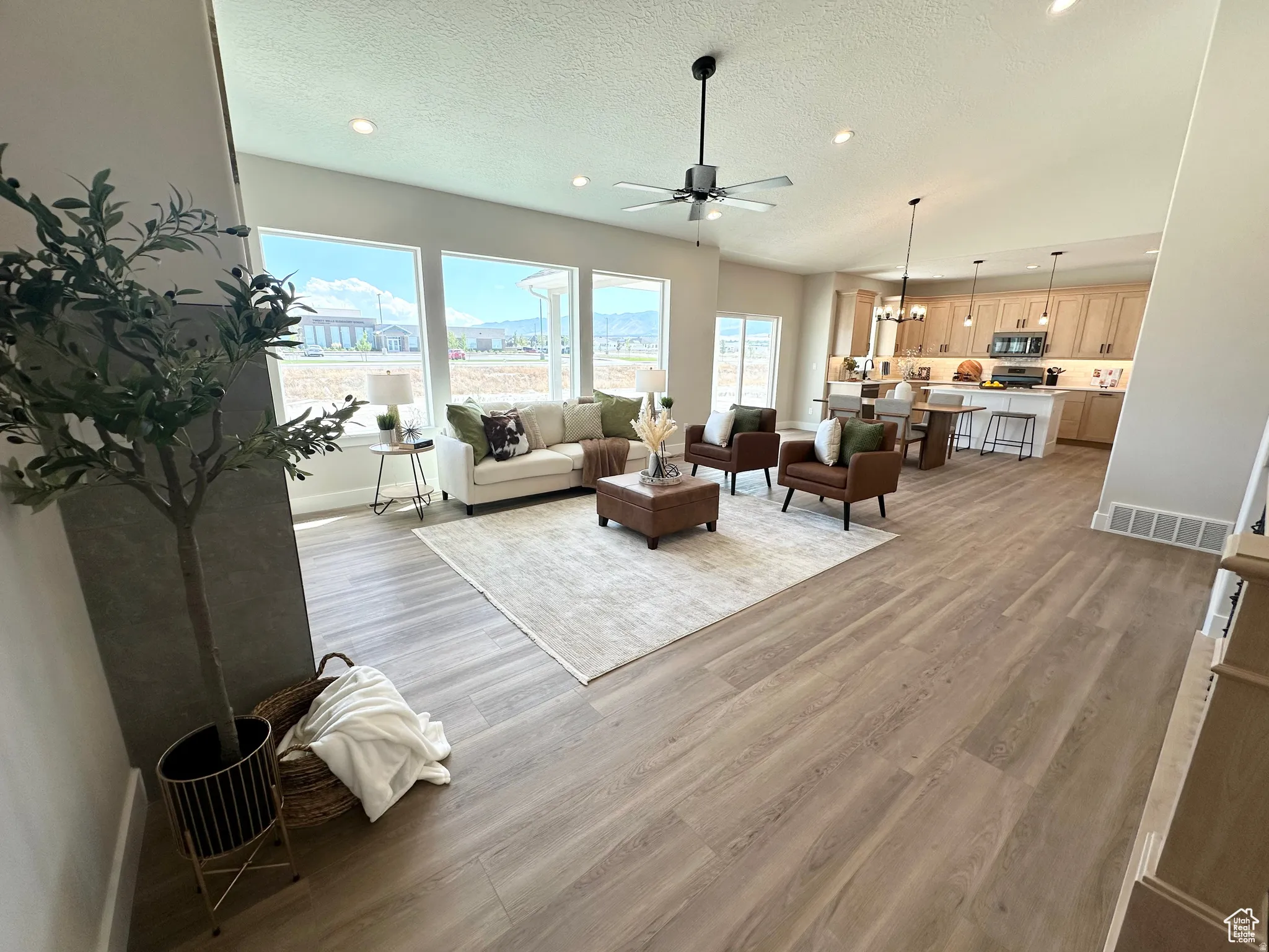 Living area featuring light wood-style flooring, a textured ceiling, ceiling fan, and recessed lighting