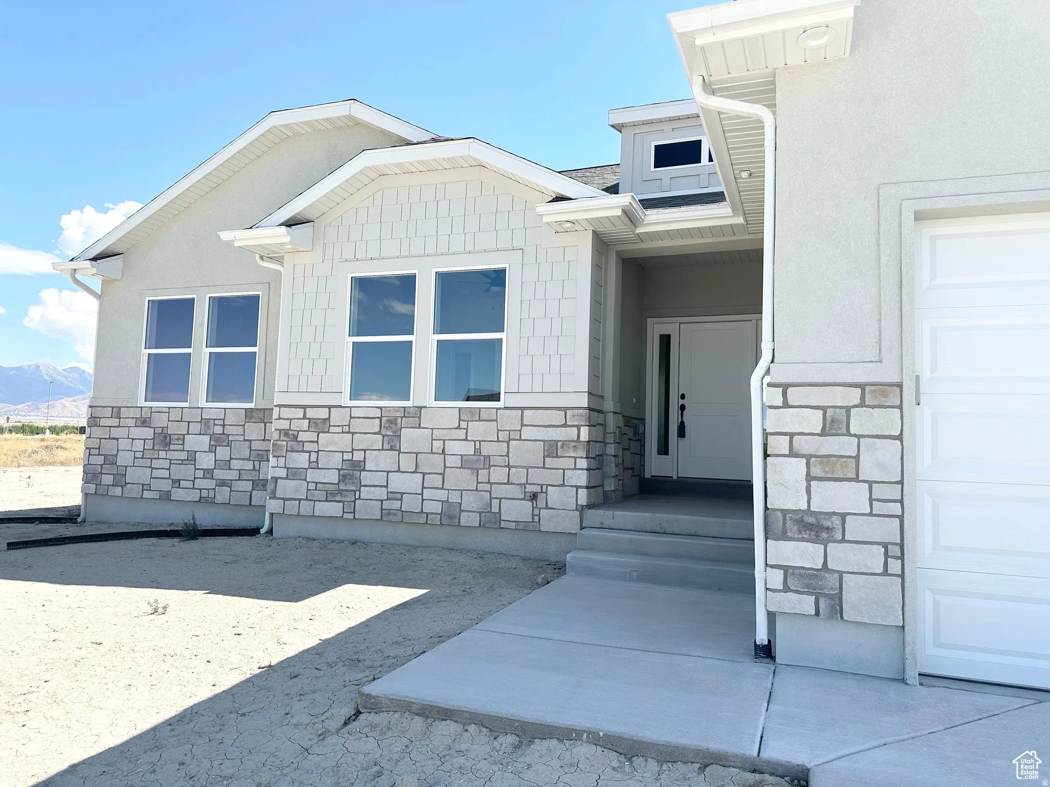 View of exterior entry featuring stone siding, a mountain view, and stucco siding