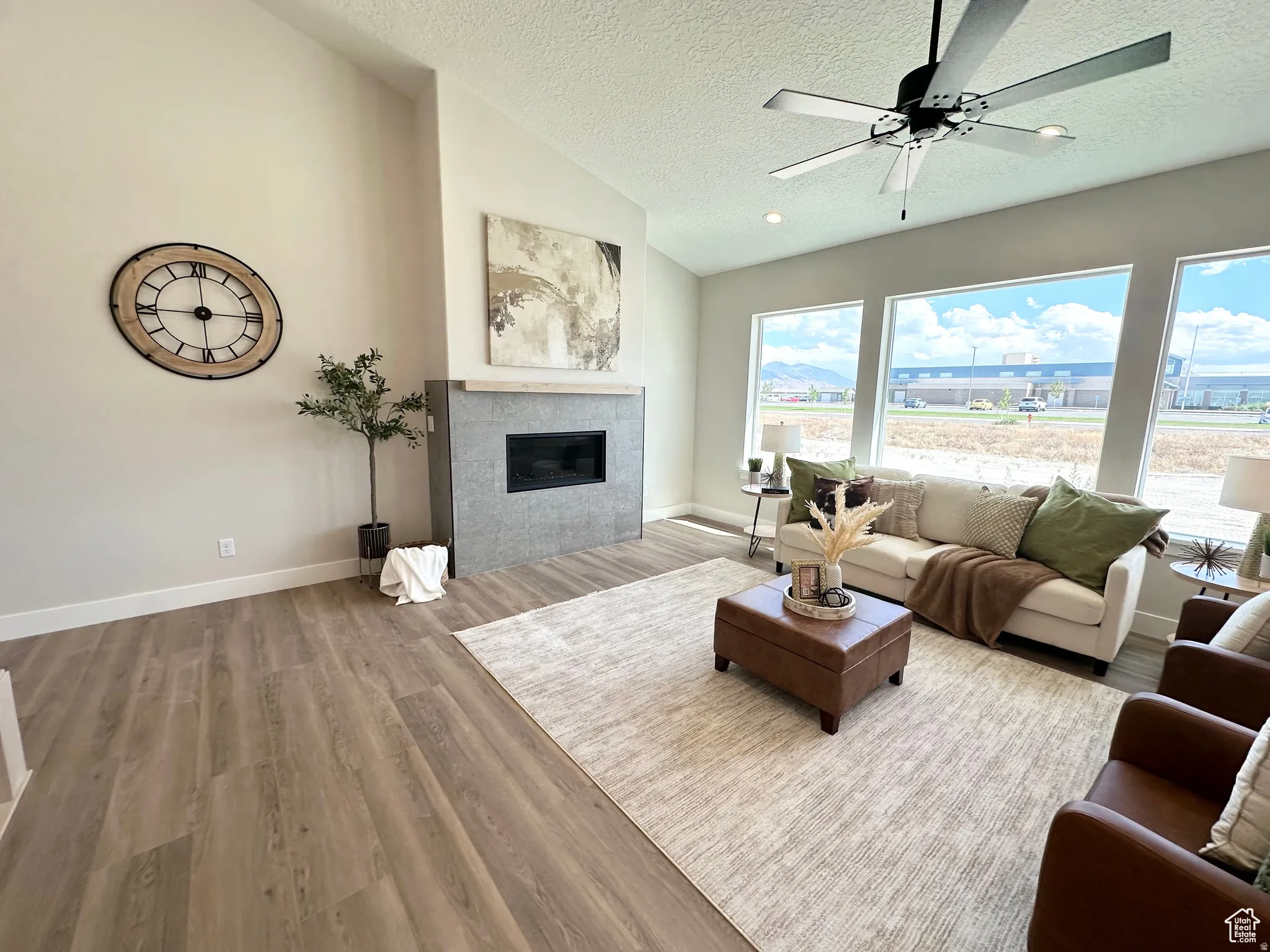 Living room with ceiling fan, light wood-style floors, and a fireplace