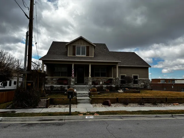 Craftsman-style home featuring stone siding, covered porch, and roof with shingles