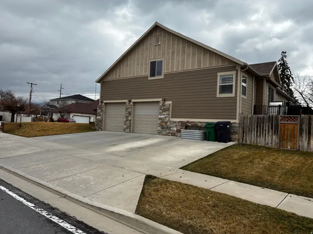 View of side of home featuring board and batten siding, concrete driveway, stone siding, and an attached garage