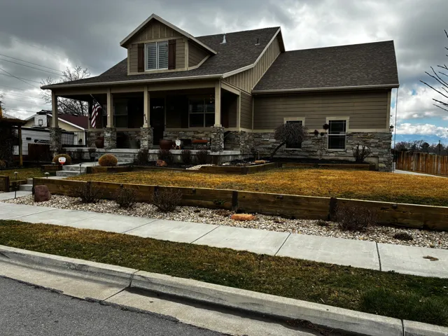 Craftsman inspired home with a porch, stone siding, and a shingled roof