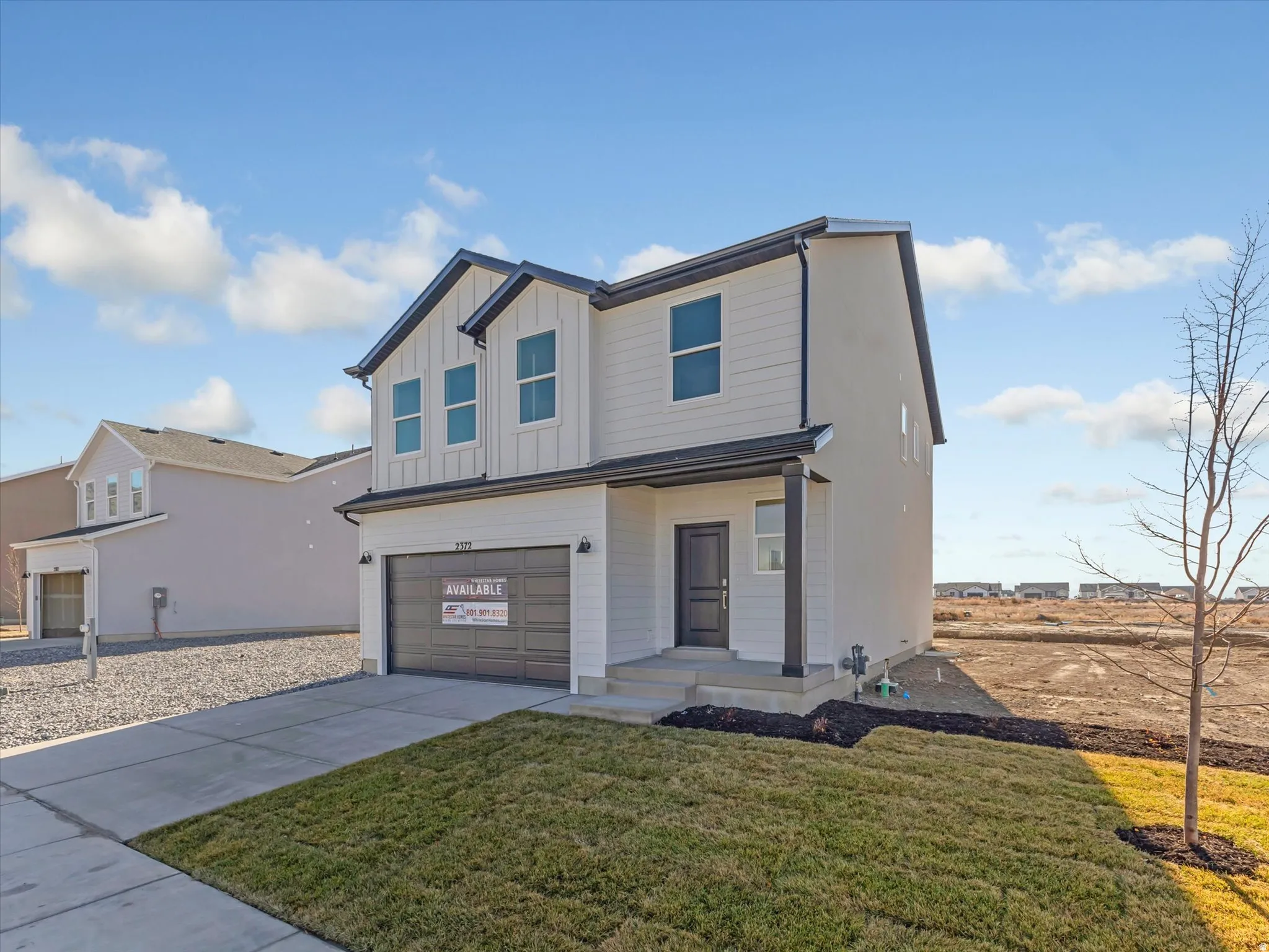 Modern inspired farmhouse with board and batten siding, a garage, concrete driveway, and a front yard