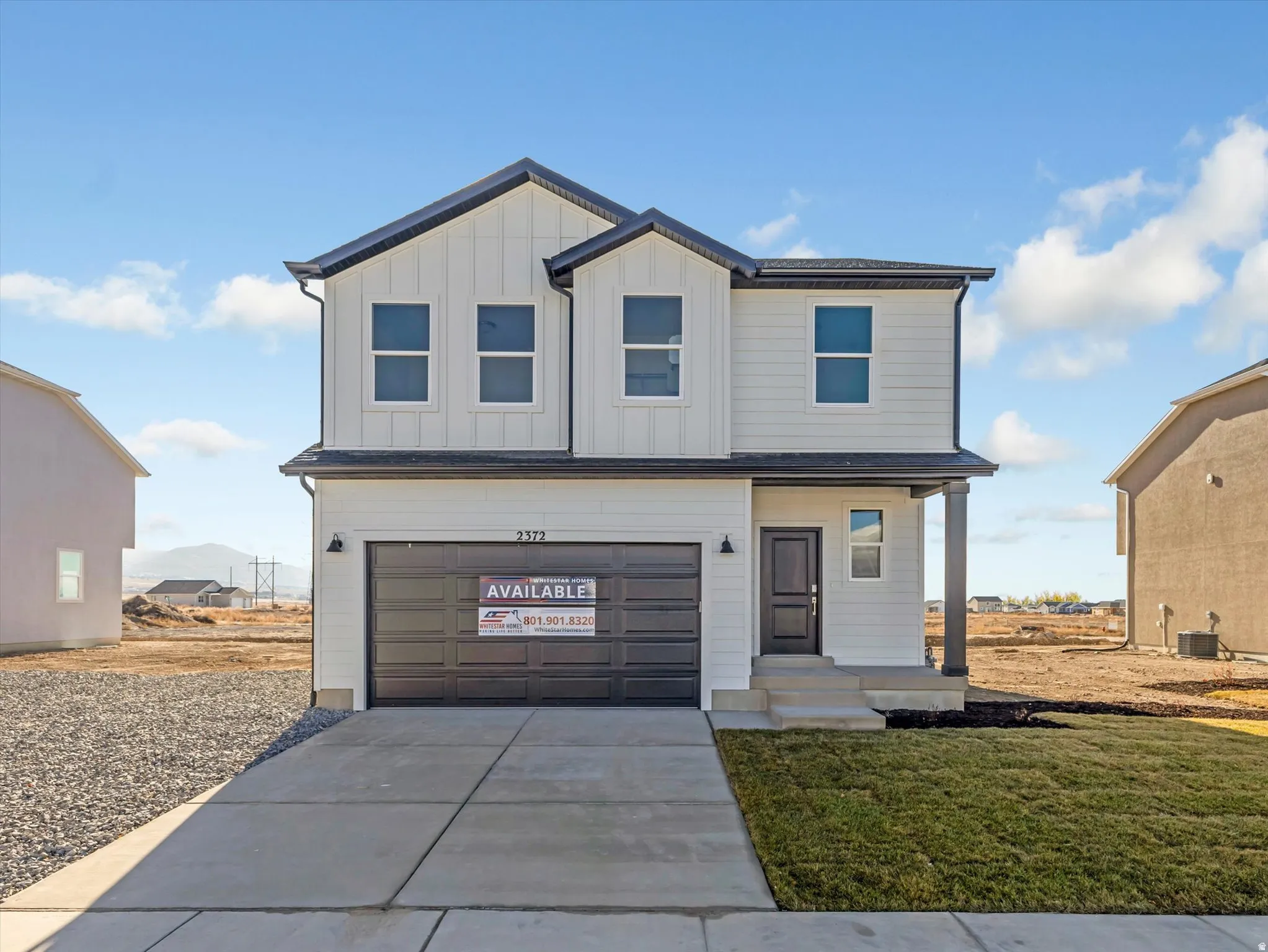 View of front of property featuring a garage, driveway, board and batten siding, and a front lawn