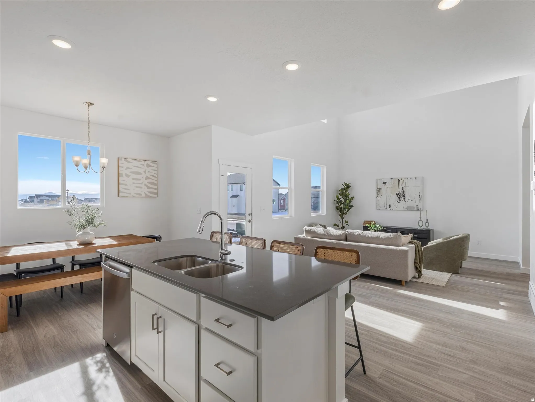 Kitchen featuring white cabinetry, a kitchen breakfast bar, open floor plan, an island with sink, and light wood-style floors