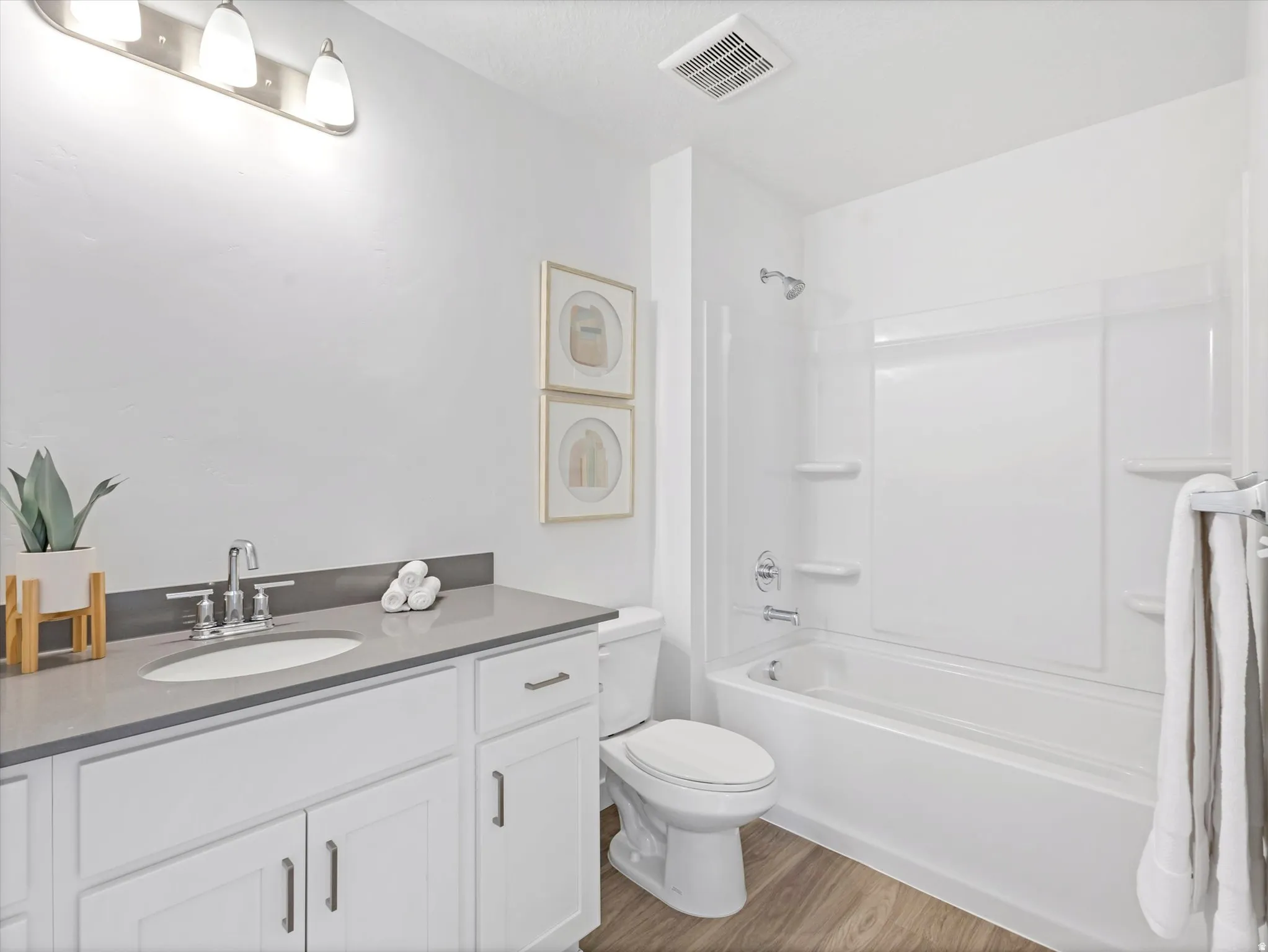 Full bath featuring vanity, washtub / shower combination, and light wood-style floors