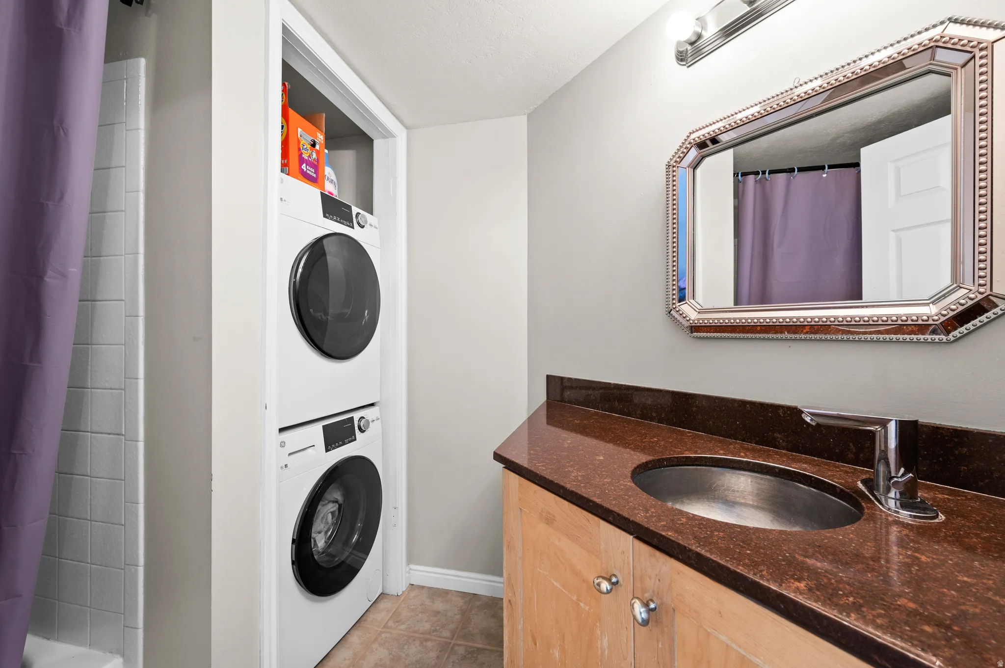 Laundry area featuring stacked washer and dryer and light tile patterned floors
