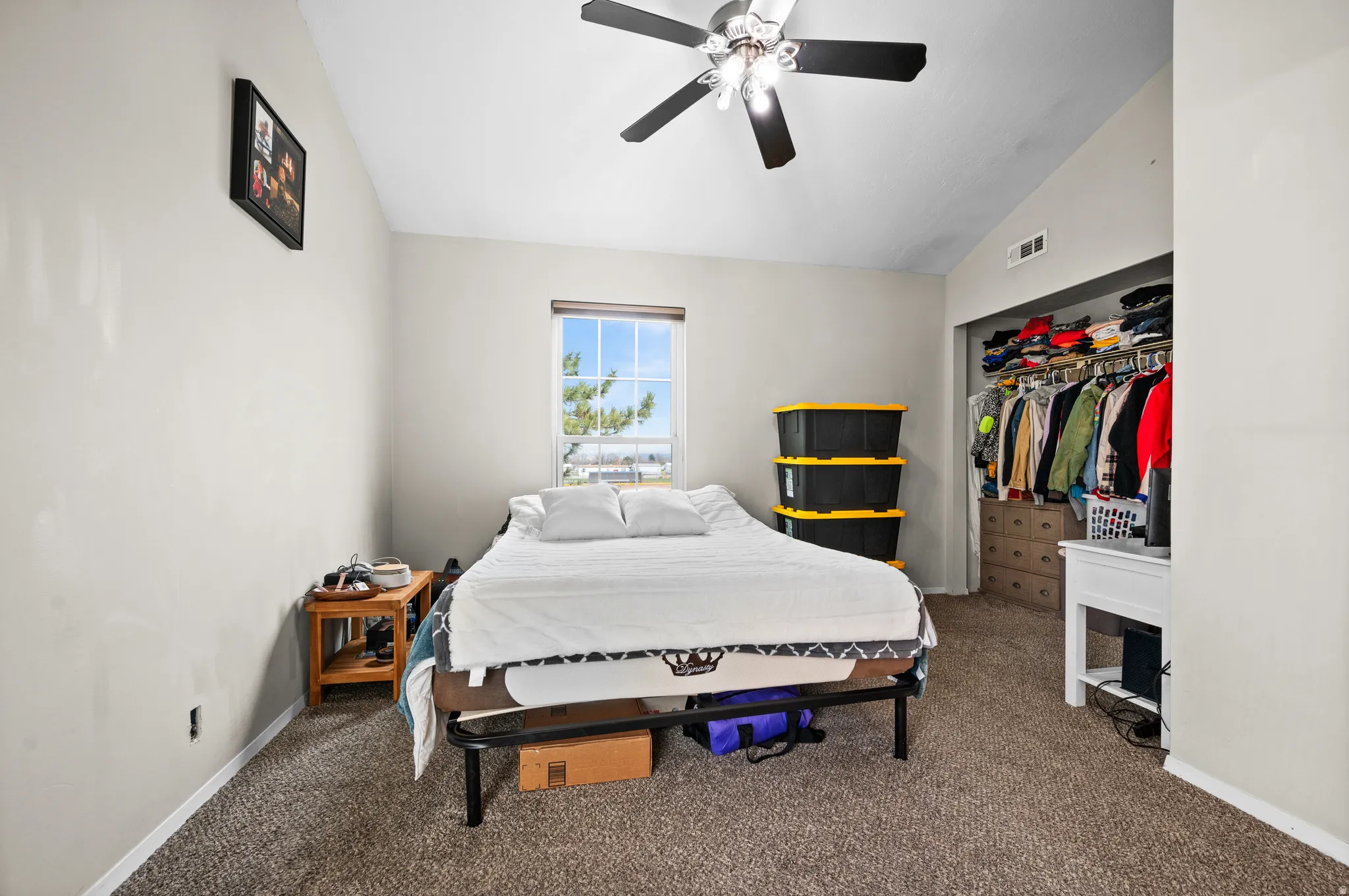 Bedroom with lofted ceiling, a closet, carpet, and a ceiling fan