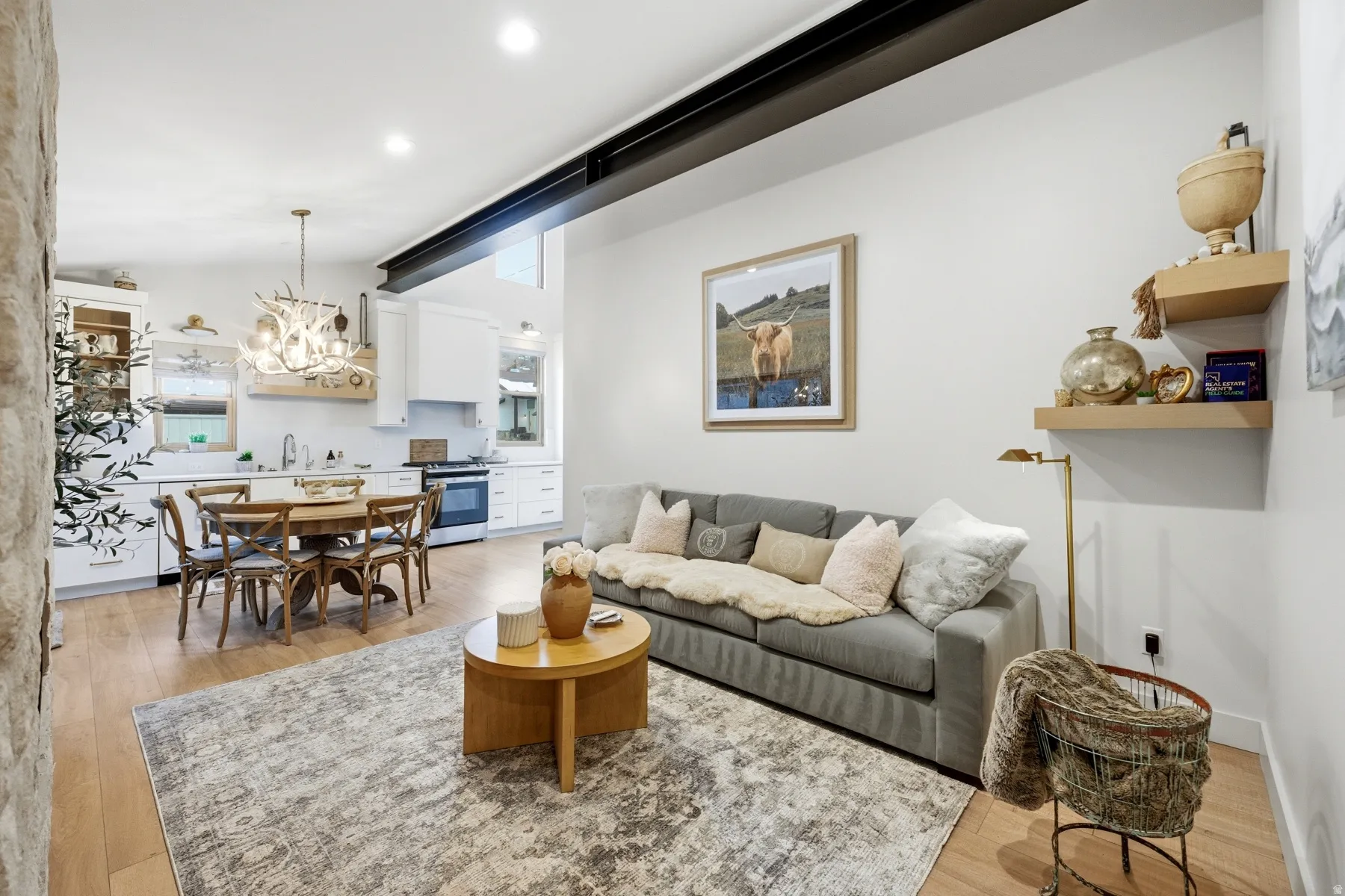 Living area with light wood-style flooring, a chandelier, and vaulted ceiling