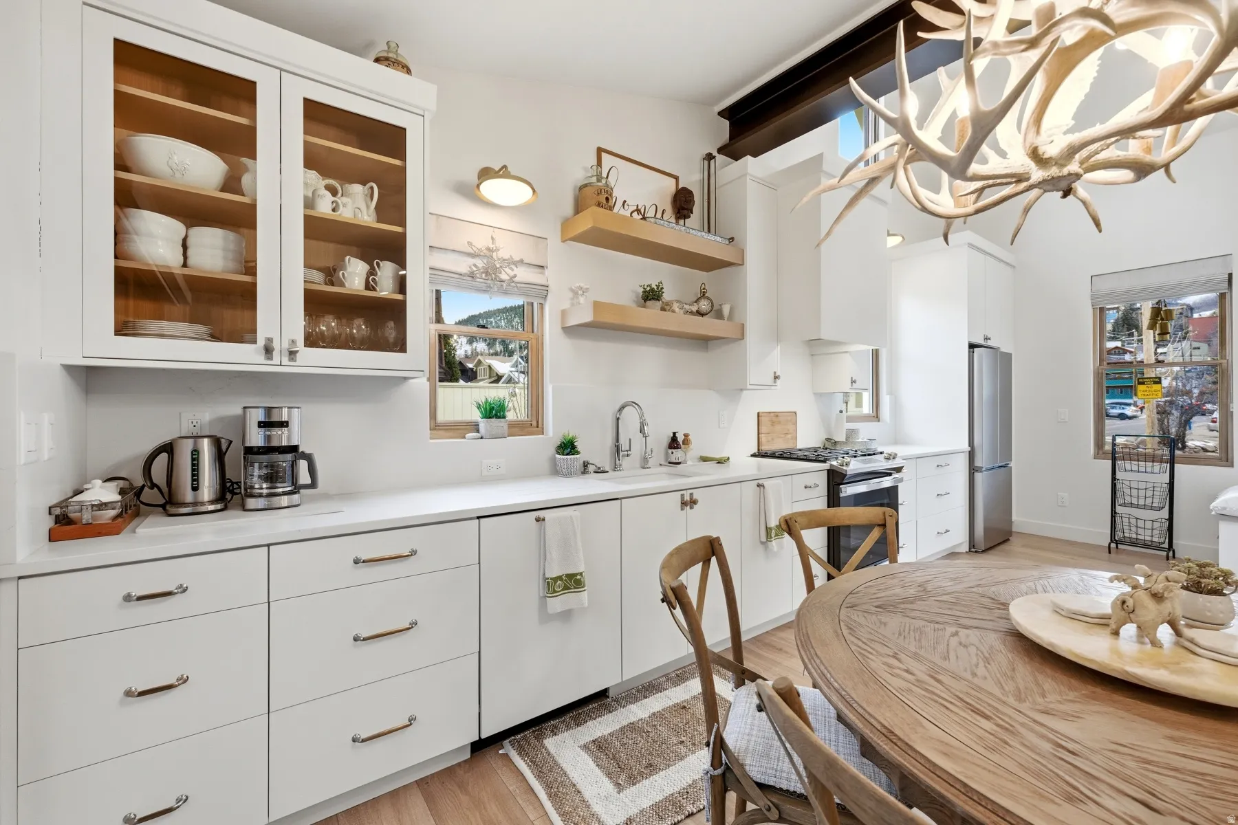 Kitchen featuring light countertops, white cabinets, stainless steel appliances, and light wood-type flooring