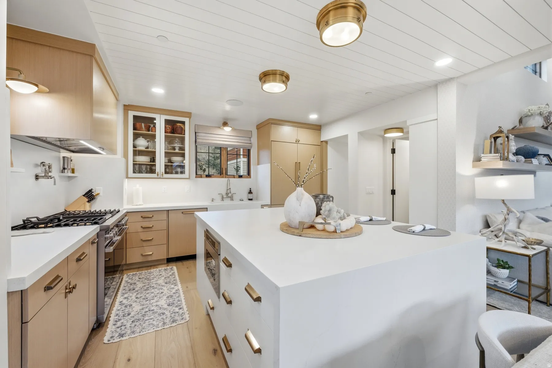 Kitchen with a kitchen island, stainless steel appliances, light wood-style flooring, glass fronted cabinets, and recessed lighting