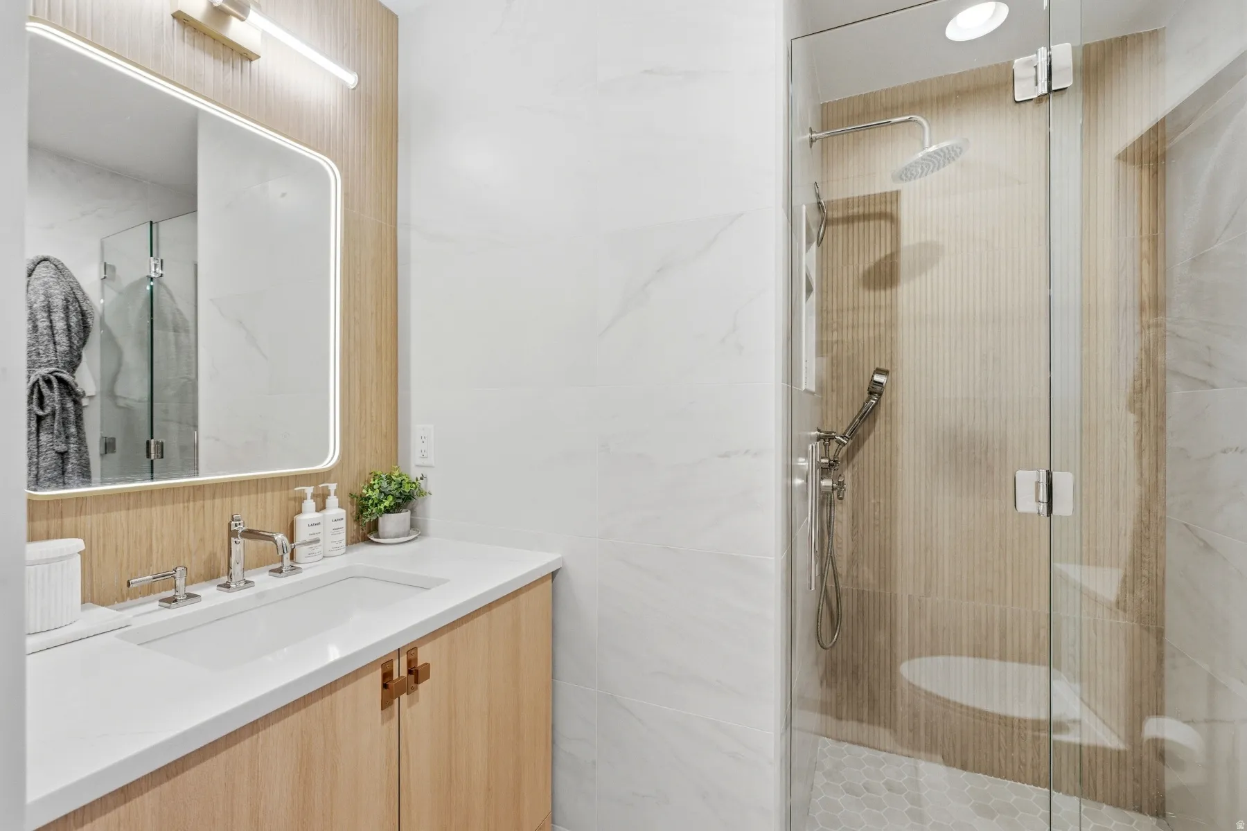 Bathroom featuring vanity, a shower stall, and tile walls