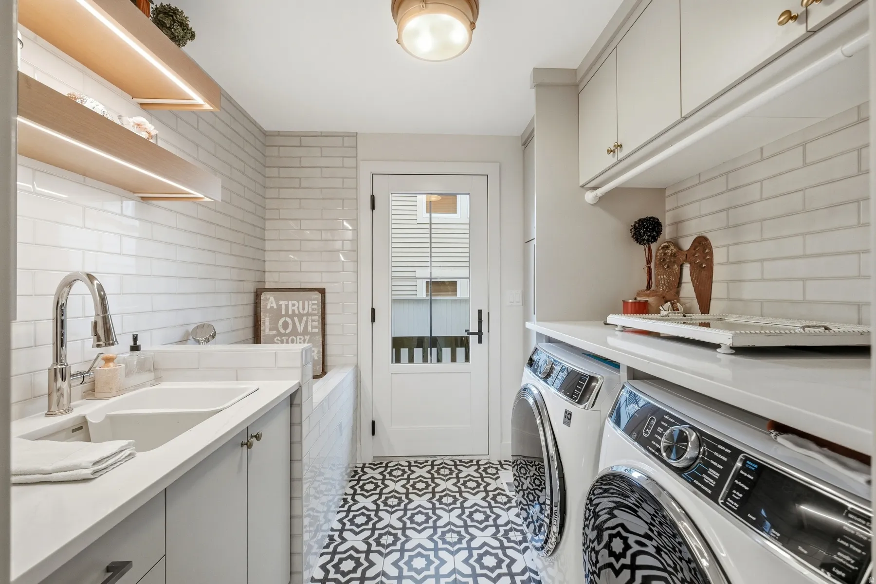 Laundry room featuring washing machine and dryer, cabinet space, and light tile patterned flooring