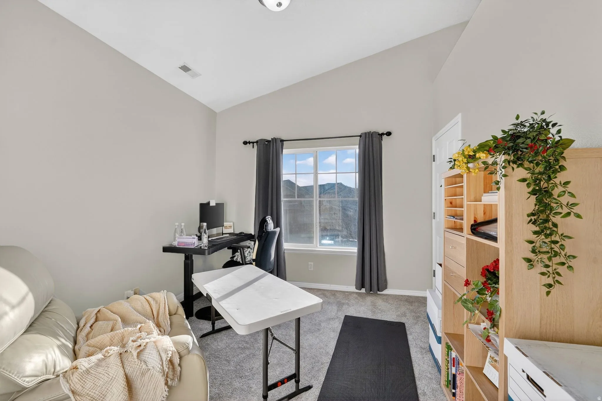 Office space with light carpet and lofted ceiling