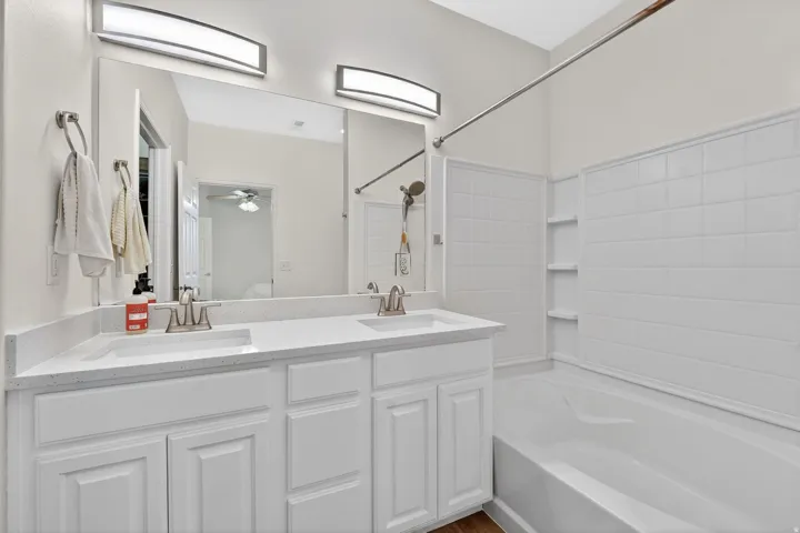 Full bath featuring double vanity, shower / bathtub combination, and a ceiling fan