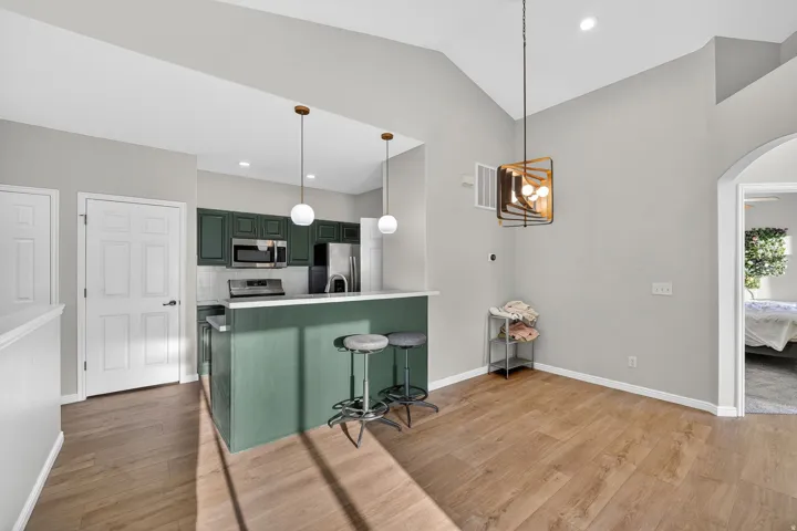Kitchen featuring green cabinets, a breakfast bar area, light countertops, stainless steel appliances, and arched walkways