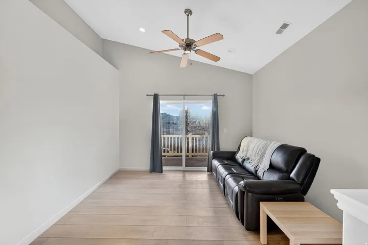 Living room featuring light wood-style flooring, ceiling fan, vaulted ceiling, and recessed lighting