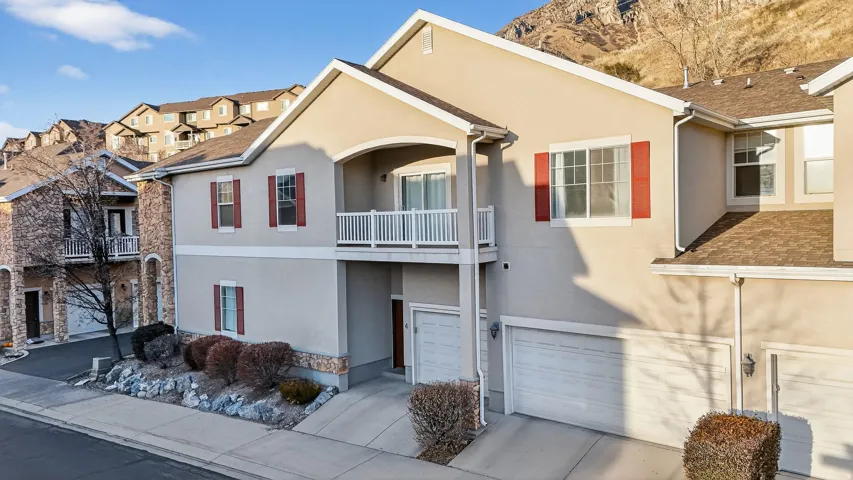 Traditional-style house with a garage, stucco siding, and a balcony