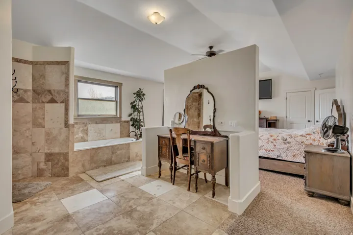 Full bathroom with a bath, ensuite bath, ceiling fan, vanity, and lofted ceiling