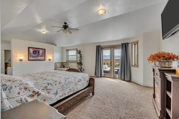 Bedroom with light carpet, access to exterior, vaulted ceiling, and a ceiling fan