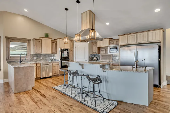 Kitchen featuring a kitchen breakfast bar, light stone countertops, tasteful backsplash, a large island, and lofted ceiling